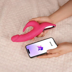 A hand hold a pink rabbit vibrator with a phone app